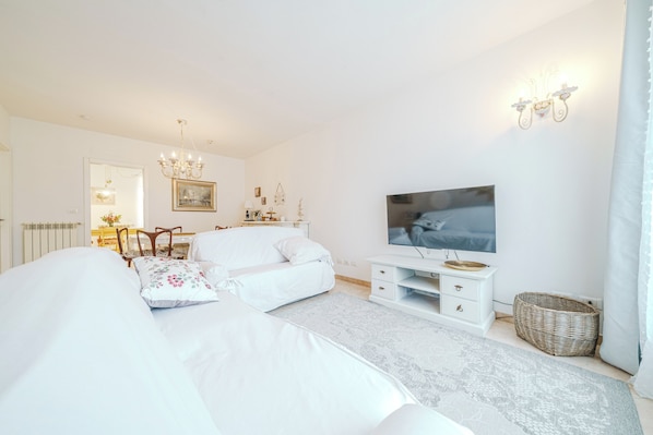 A modern bedroom with a large bed, a TV, a dresser, and a chandelier.