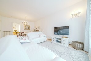 A modern bedroom with a large bed, a TV, a dresser, and a chandelier. - Casa Sarabè - Dorno Motocross Track (Dorno)