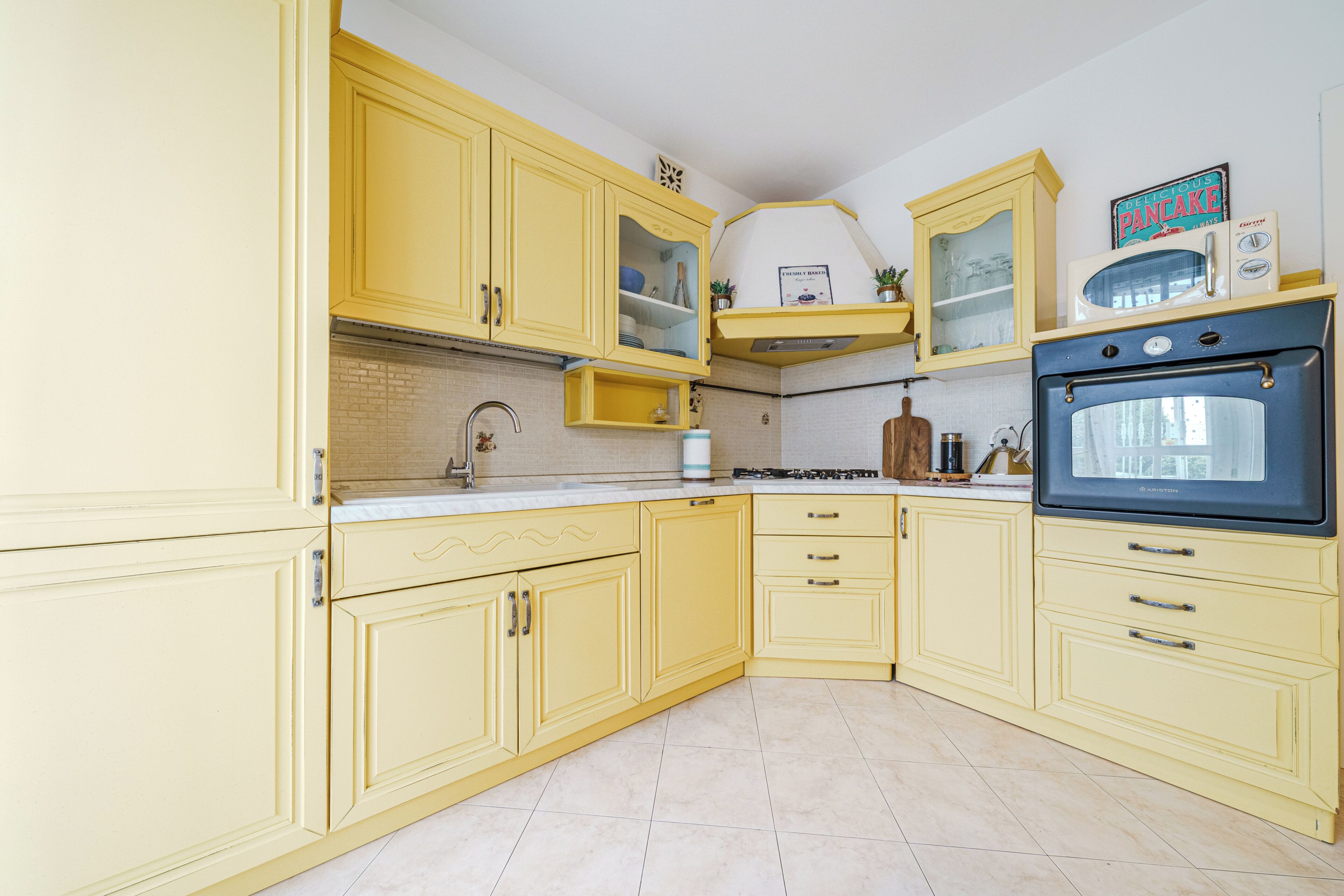 A kitchen with yellow cabinets, a microwave, and an oven.
