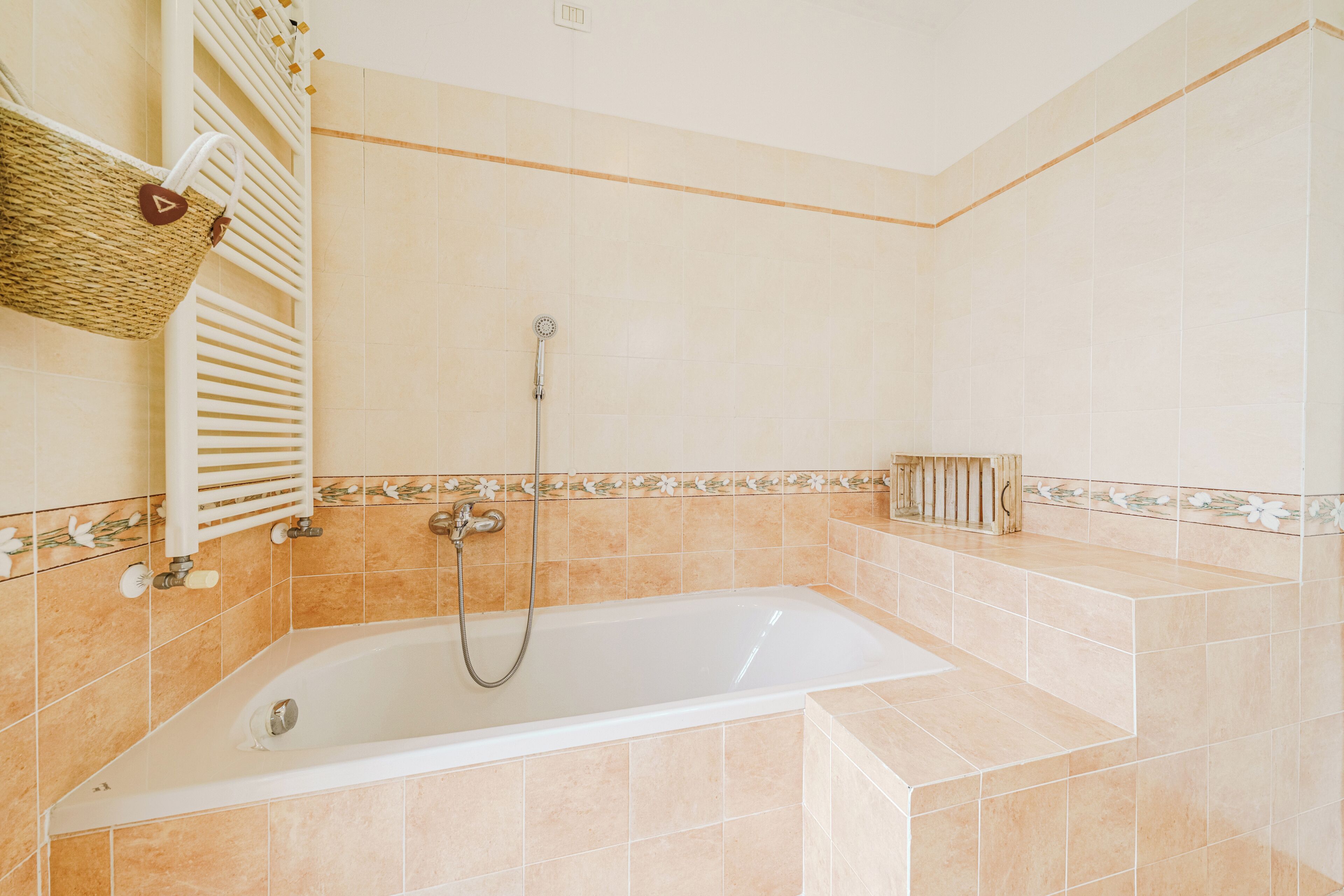A bathroom with a bathtub, shower, and a towel rack with a basket.