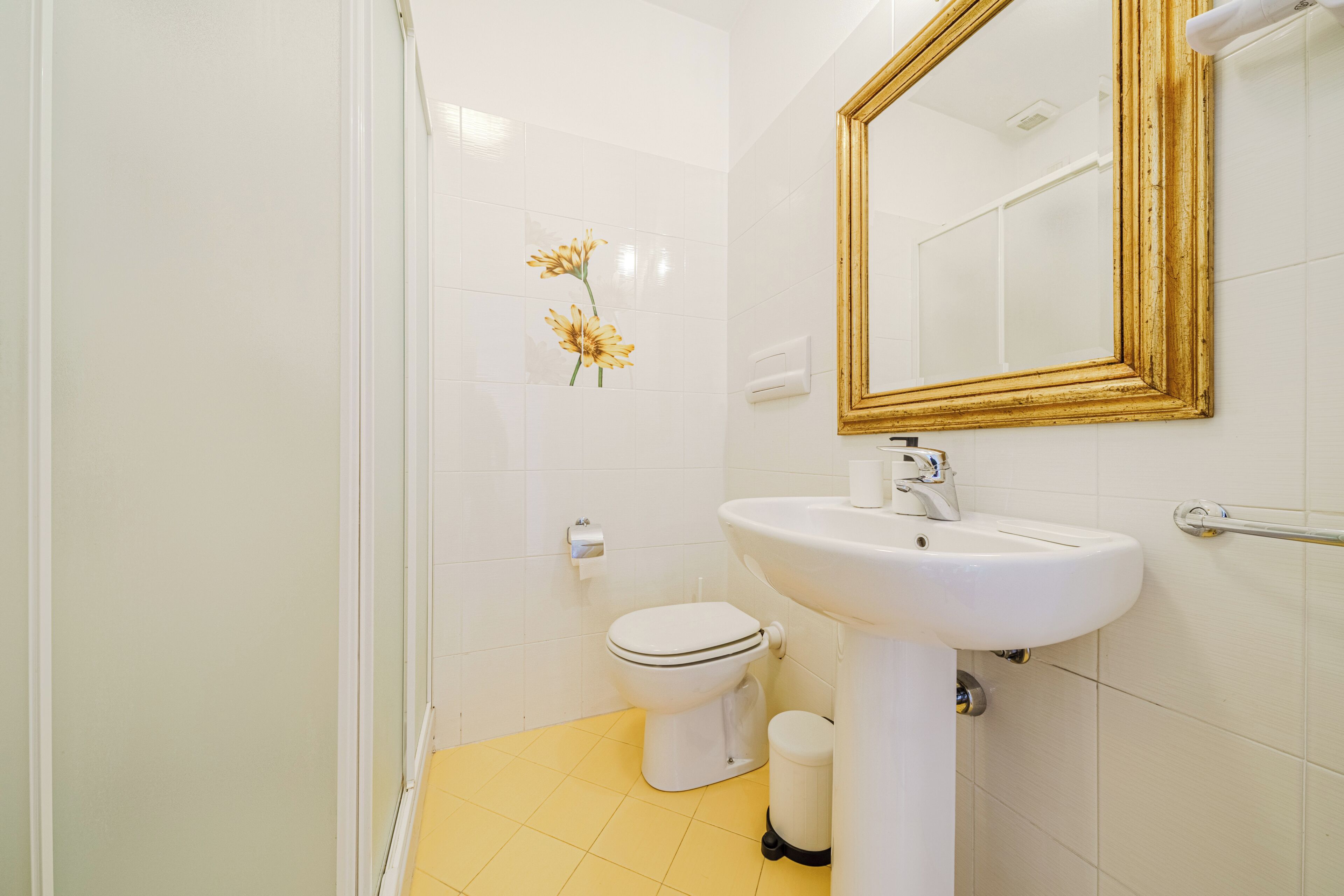 Un baño con lavamanos, inodoro y ducha blancos.