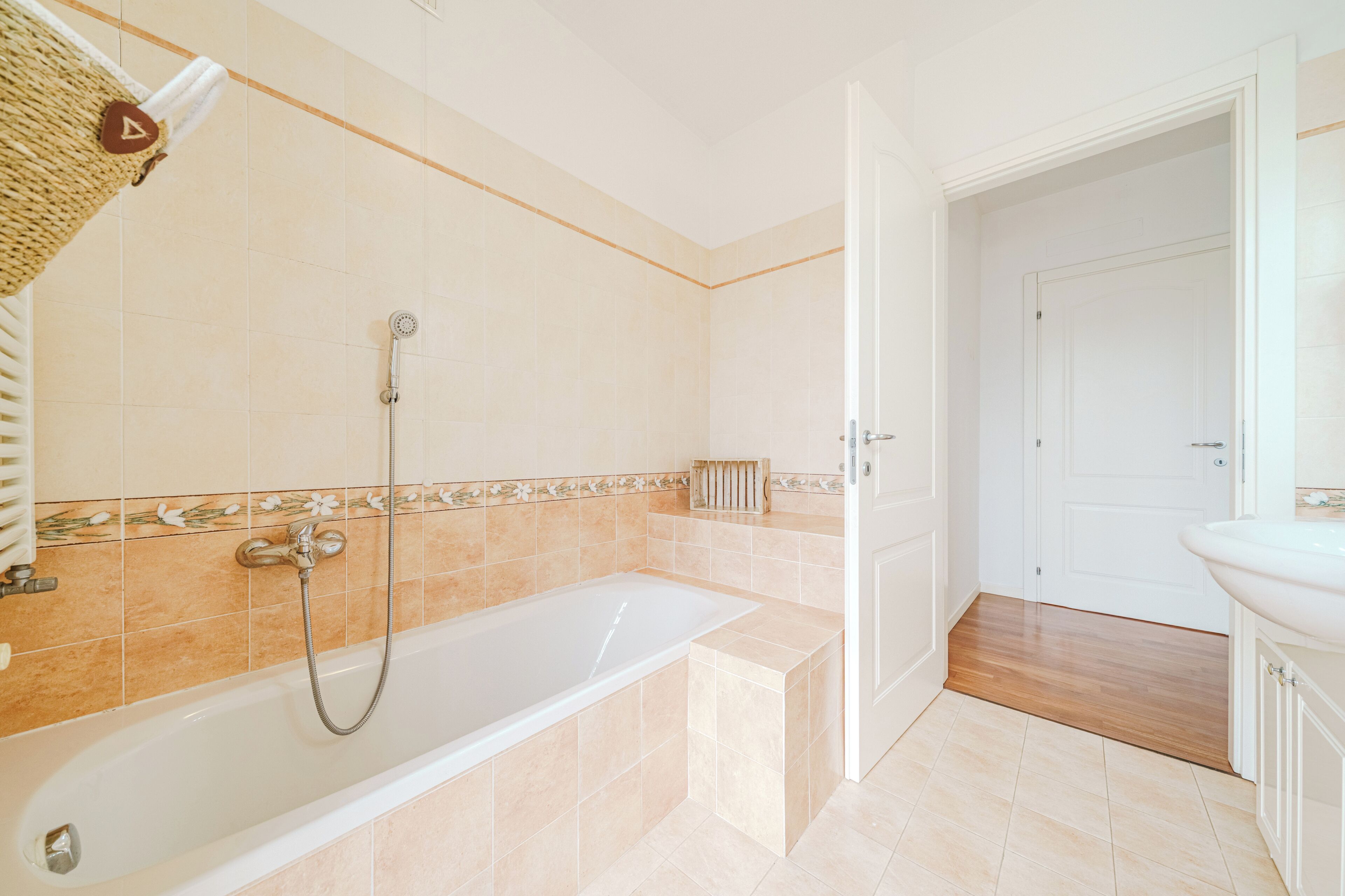 Une salle de bain avec une baignoire, une douche et une porte blanche donnant sur une autre pièce.