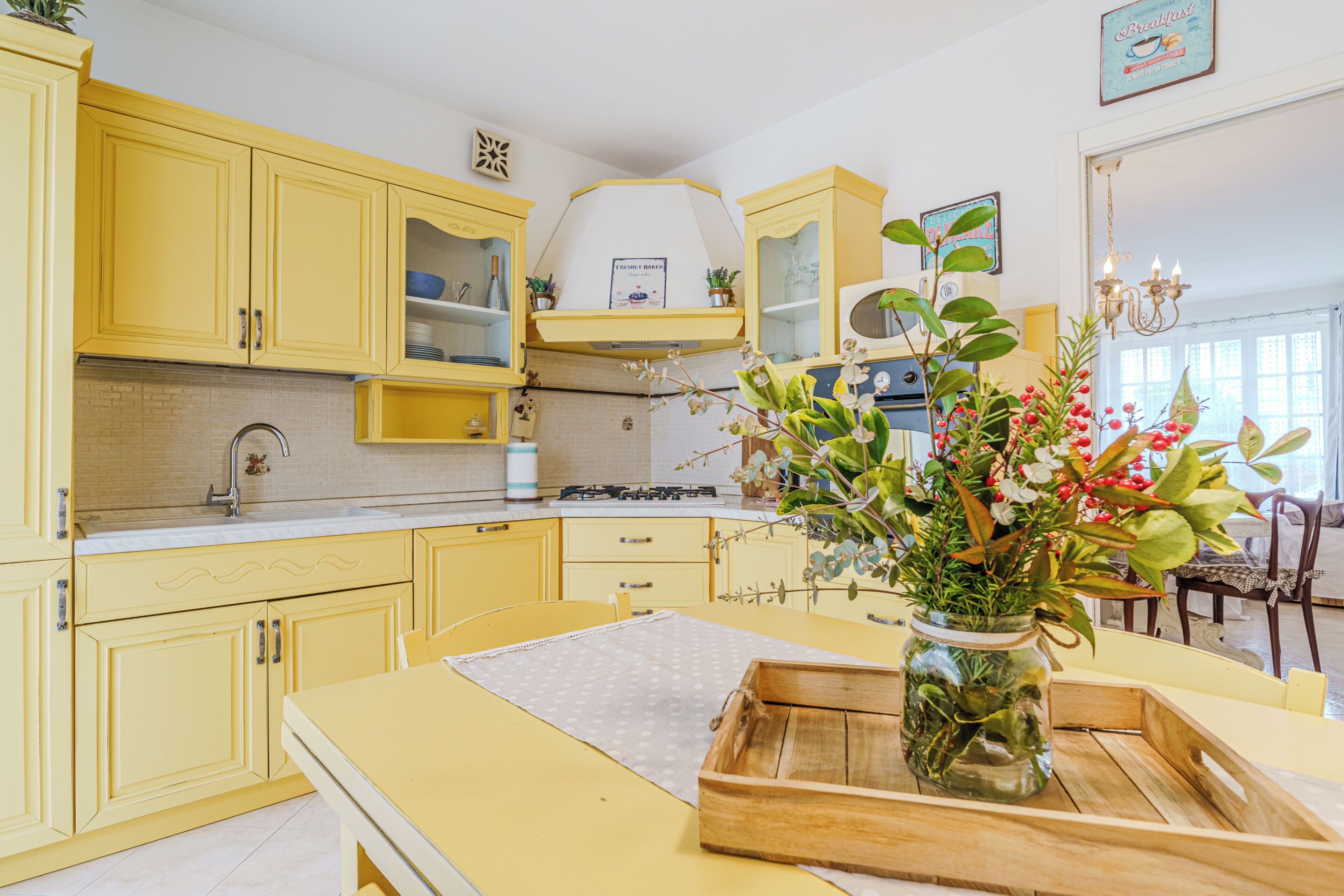 A yellow kitchen with a central island, a stove, and a sink.