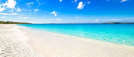 A beach with clear turquoise water and a sandy shore.