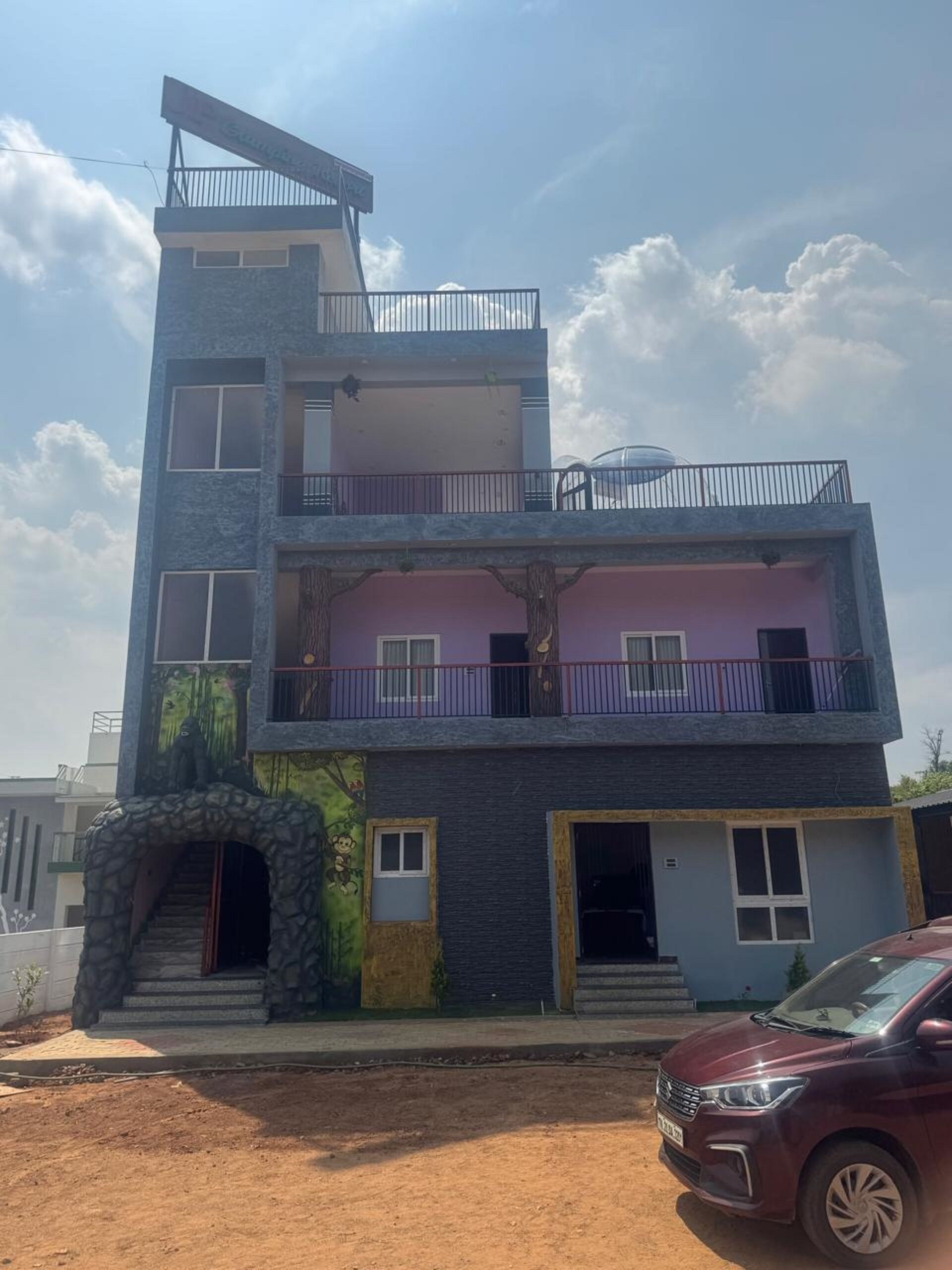 A multi-story building with a balcony, a staircase, and a car parked in front.