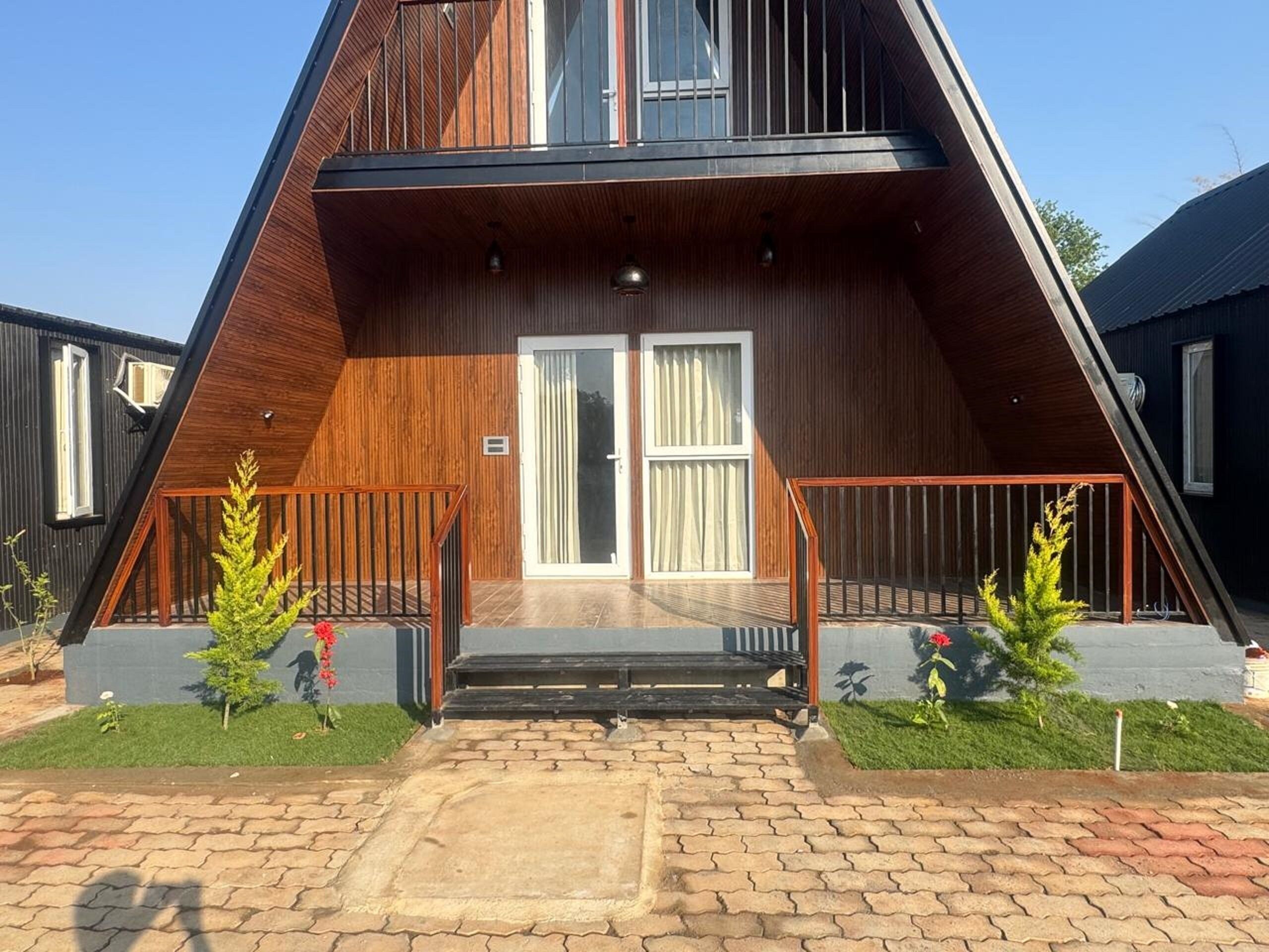 Ein modernes Gebäude mit einem dreieckigen Dach, Holzfassade und einem zentralen Eingang mit Glastüren.