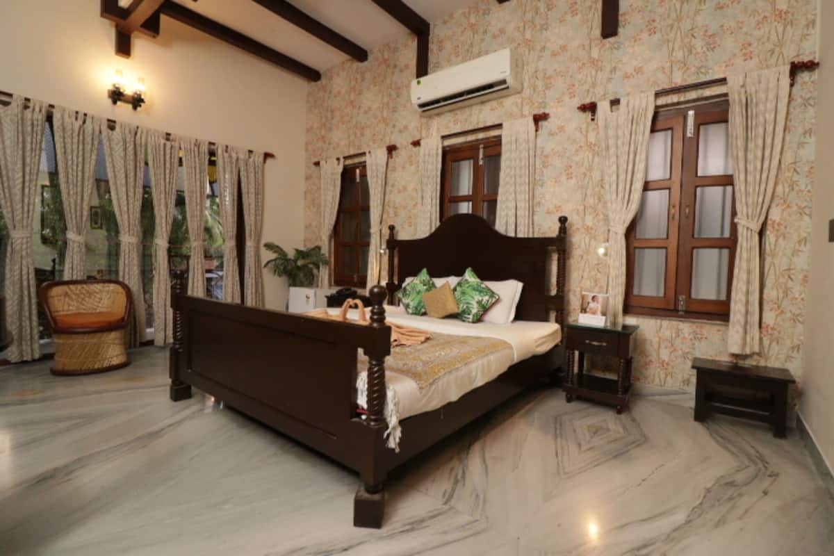 Un dormitorio con una cama de madera, una planta en maceta, una silla y una mesita de noche.