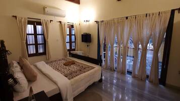 Un dormitorio con una cama, cortinas, un televisor y una ventana.