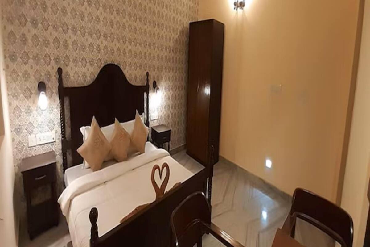 Un dormitorio con cama, mesitas de noche, armario, silla y mesa.