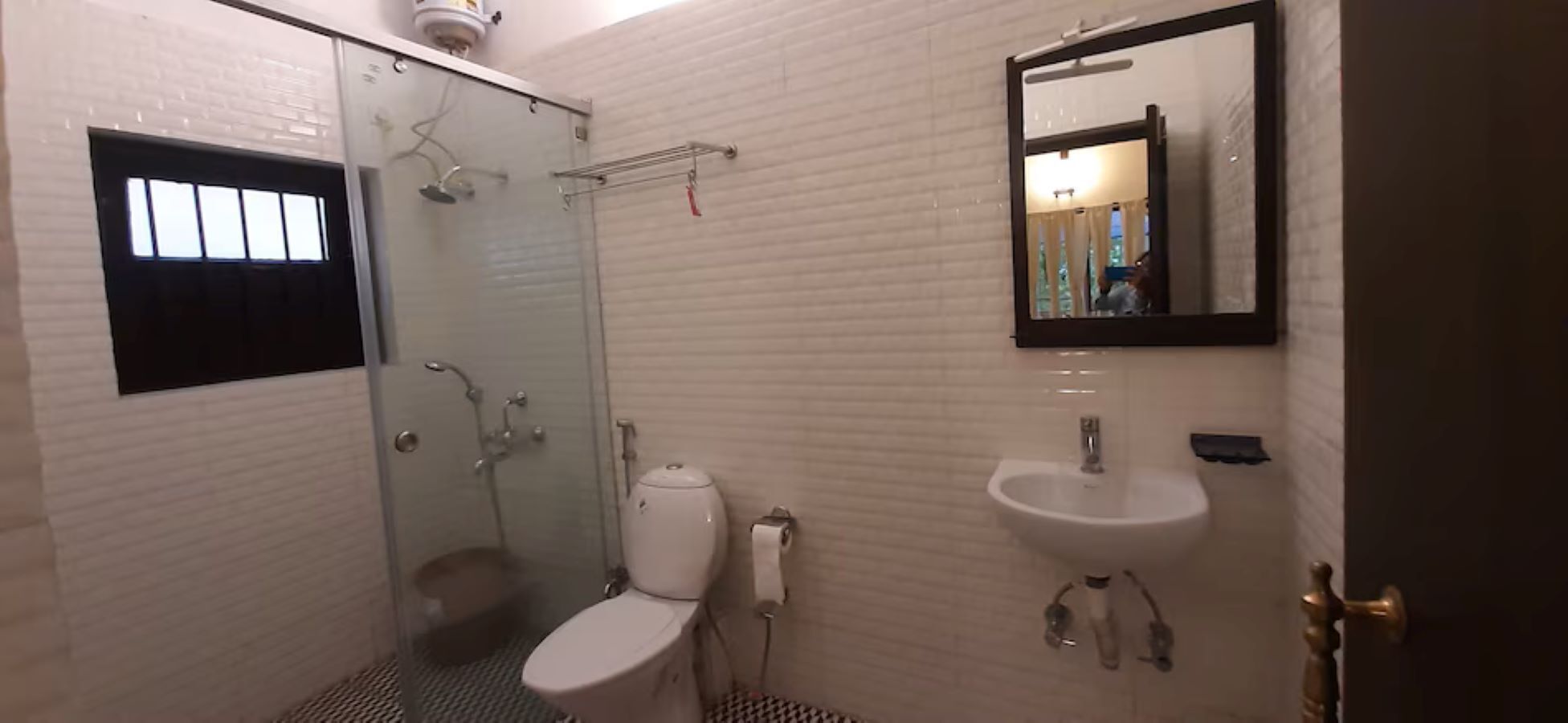 Un baño con ducha de vidrio, inodoro, lavamanos y espejo.