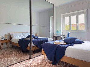 Ein Schlafzimmer mit zwei Betten, einem großen Spiegel, einem Schreibtisch und einem Fenster.