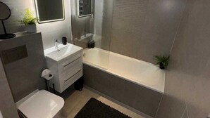 Een moderne badkamer met toilet, wastafel en bad.