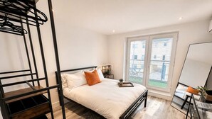 A bedroom with a bunk bed, a desk, a chair, a window with a view, and a small table with a plant. - The Studios at Taylor’s Court (Canvey Island)