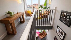 A staircase with a wooden bench, two leather chairs, a neon sign, and framed pictures on the walls. - The Studios at Taylor’s Court (Canvey Island)