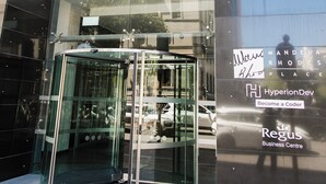 Ein Gebäudeeingang mit Glastür und einem Schild, auf dem 'Mandela Rhodes Place' steht.