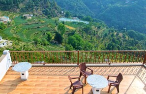 Eine Terrasse mit Blick auf stufenförmig angelegte Felder und ein Gebäude in der Ferne.