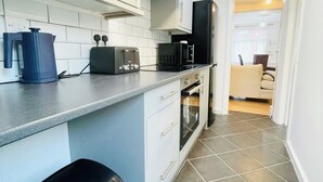 Eine kompakte Küche mit weißen Schränken, einem schwarzen Toaster, einer Kaffeemaschine und einer Mikrowelle.