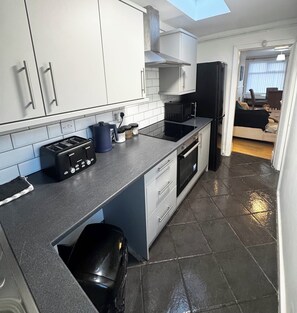 A modern kitchen with white cabinets, a black refrigerator, and a built-in oven.