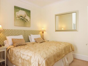 A hotel room with a bed, two bedside tables, a wall-mounted mirror, and a floral painting. - Avenue Park Villa (Torquay)