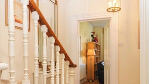 A staircase with white balusters and a wooden handrail leading to a room with a lamp and a shelf. - Avenue Park Villa (Torquay)