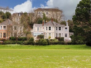 A row of houses with a grassy field in the foreground. - Avenue Park Villa (Torquay)