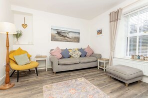 Una sala de estar con sofá, sillón, reposapiés y alfombra.