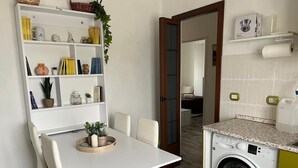 A compact living space with a dining area, a washing machine, and a small kitchenette. - Valle dei Casali House is 5 minutes from Villa Pamphili and 15 minutes from the Vatican. (Roma)