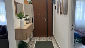 A hallway with a wooden door, a small rug, a plant, a mirror, and a bed with a blue pillow. - Valle dei Casali House is 5 minutes from Villa Pamphili and 15 minutes from the Vatican. (Roma)