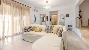 Una sala de estar moderna con un conjunto de sofá, un espejo y una escalera que sube a otro nivel.
