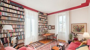 Una sala de estar acogedora con una amplia estantería, un comedor y un sofá rojo intenso.