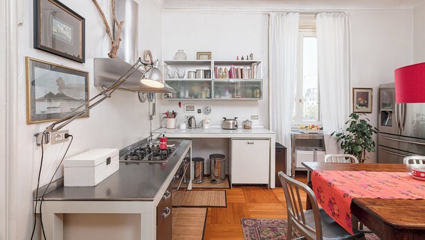Cocina compacta con estufa a gas, un lavamanos y zona de comedor con mesa y sillas.