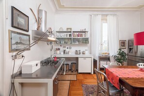 A compact kitchen with a gas stove, a sink, and a dining area with a table and chairs. - The House of wisteria (Milano)