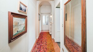 Un pasillo con alfombra estampada, paredes blancas y puertas de madera.