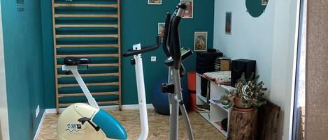A home gym with exercise equipment, a basketball hoop, and a wooden floor.