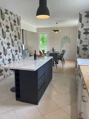 Una cucina moderna con isola centrale, mobili scuri e zona pranzo con vista sul verde.