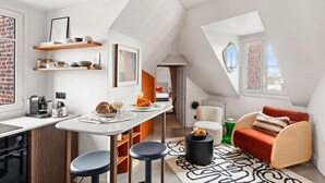 Ein modernes Loft mit Küche, Essbereich und einer gemütlichen Sitzecke mit einem roten Sessel und einem kleinen Tisch.