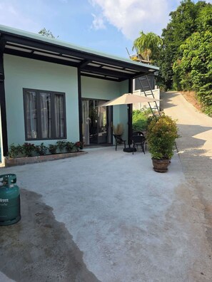 A building with a covered patio, a gas cylinder, and a potted plant.