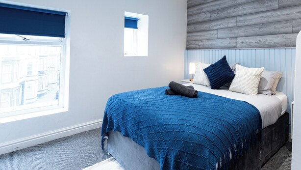 Ein Schlafzimmer mit Bett, Fenster, Nachttisch und Kopfteil.