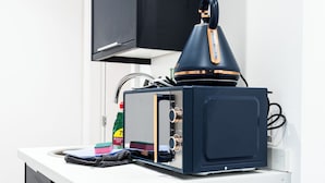 Eine kleine Küche mit Mikrowelle, Wasserkocher und einem Schrank.