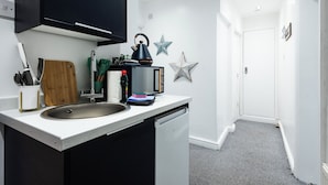 Eine moderne Küche mit Spüle, Toaster und Wasserkocher. An der Wand befinden sich Sterne als Dekoration und eine Tür zu einem anderen Raum.