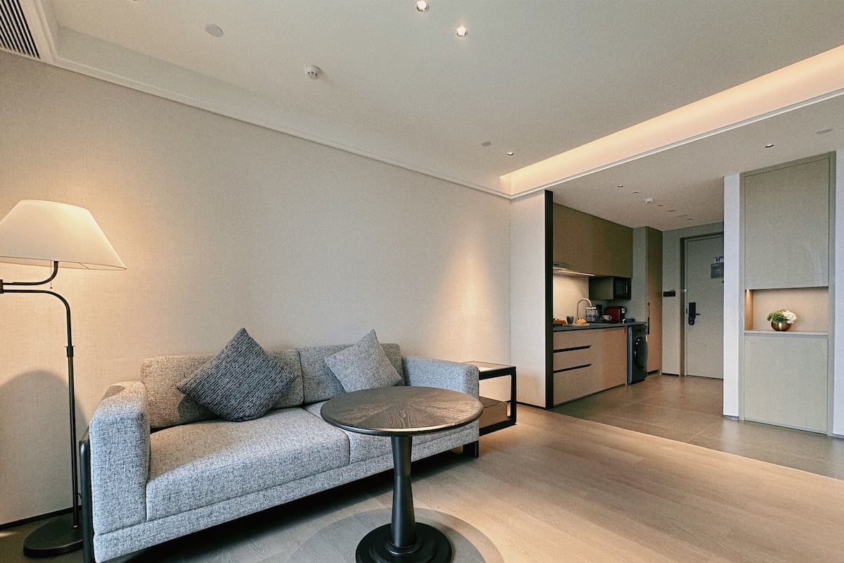 A modern living room with a sofa, a round table, and a lamp.