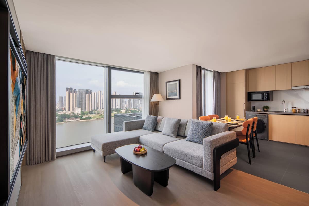 A modern living room with a sofa, a dining table, and a kitchen area with a microwave.