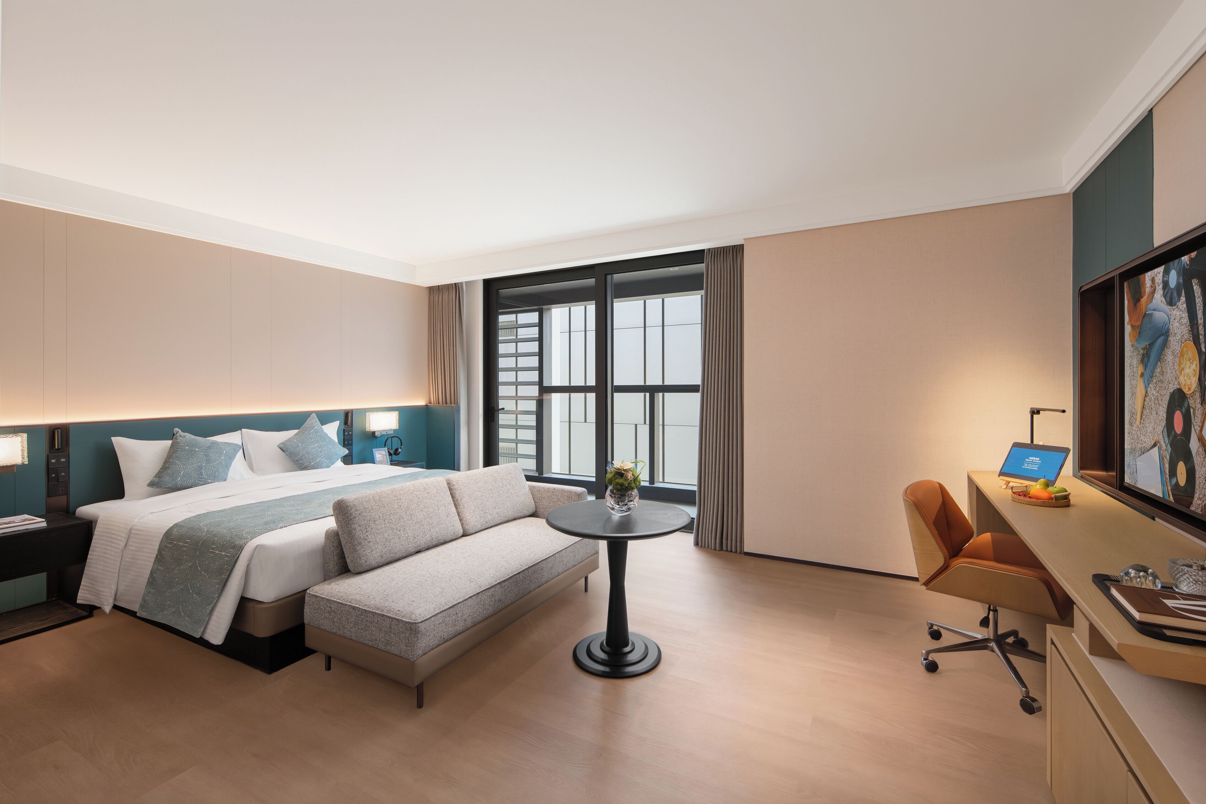 Une chambre d’hôtel moderne équipée d’un lit, d’un canapé, d’un bureau et d’une grande fenêtre.