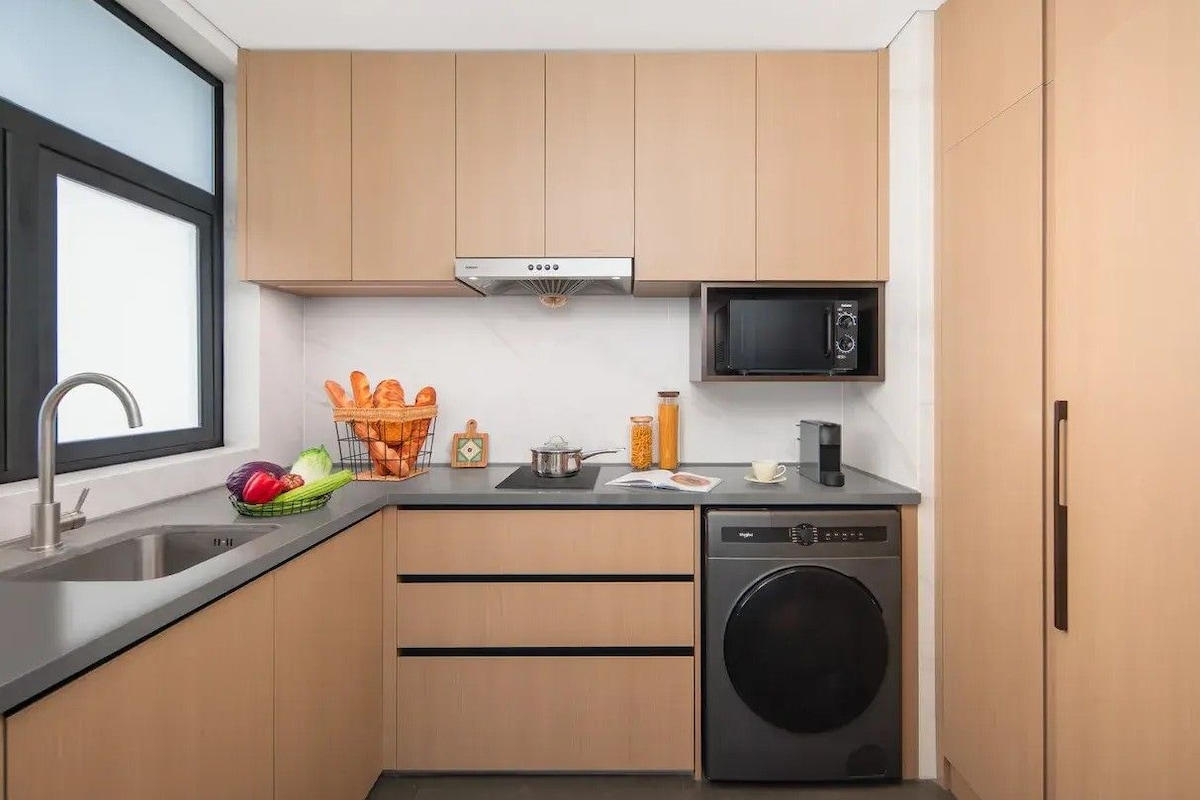 A compact kitchen with a dishwasher, microwave, and a window providing natural light.