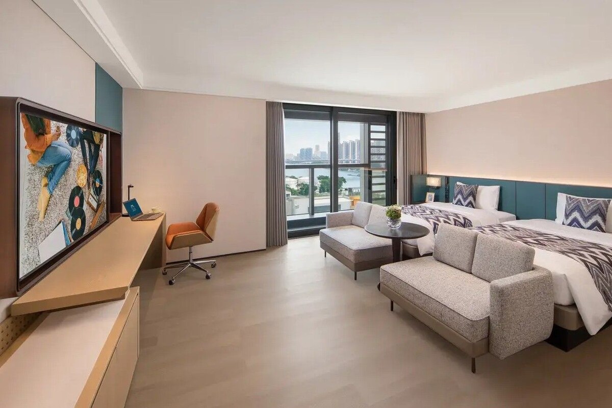 Une chambre d’hôtel moderne avec un grand lit, un canapé, un bureau et un tableau au mur.