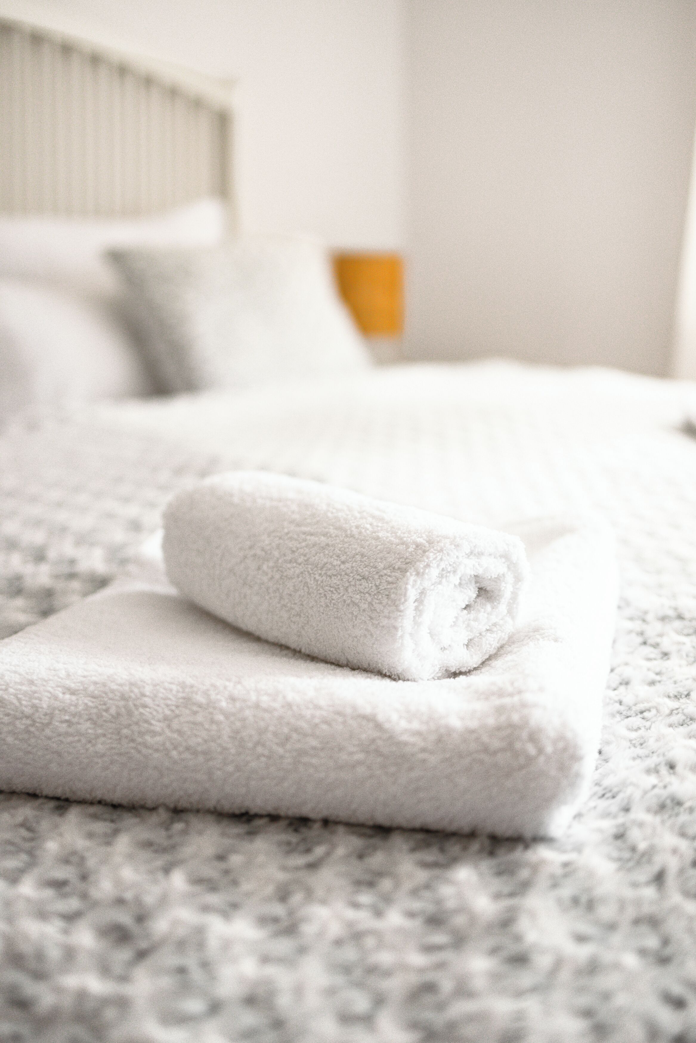 Een net opgemaakt bed met witte handdoeken en een geborreld deken.