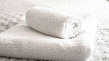 Een net opgemaakt bed met witte handdoeken en een geborreld deken.