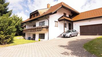 Een woonhuis met twee verdiepingen, een auto op de oprit, een balkon en een garage.