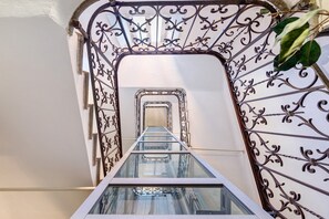 Eine gläserne Treppe mit aufwendiger Metallgeländer und freiem Blick auf die darüber liegende Etage.