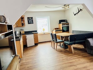 Eine moderne Küche mit Holzausbau, einem eingebauten Backofen und einem Essbereich mit einer Bank und Stühlen.